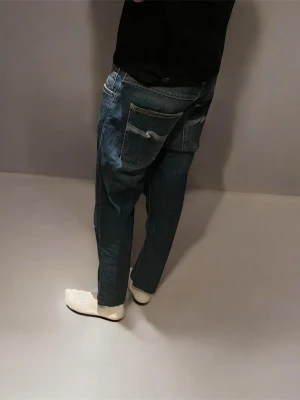 Mörkblå Grim Tim nudie jeans - Säljer ett par mörkblå nudie jeans i modellen Grim Tim. Jeansen är i bra skick utom att de är avklippta längst ner på dem(se bild 7). Därför vet jag inte riktigt vilken storlek de är. Men det är w31 och jag är 175 och är lite korta på mig. Passar nog bäst för dig runt 170. Skriv vid fler frågor.