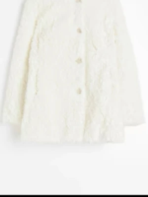 Vit teddyjacka  i Pile med knappar - Mysig vit teddyjacka med lång ärm och knäppning framtill. Jackan har en fluffig struktur och rak passform som ger en trendig look. Perfekt för dig som vill ha en varm och stilren jacka till höst och vinter.