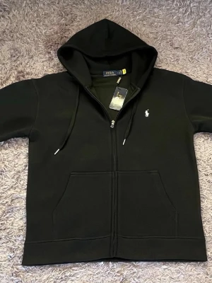 Polo Ralph lauren tröja med dragkedja - Hej!  Jag säljer en vit Ralph lauren kofta. Den är helt ny och har bara testat den en gång, den har väldigt bra kvalité och passar för alla årstider. Jag säljer den eftersom jag fick den i present och den var lite för stor. Den passar både M och L men hade nog sutit bättre på M. På storleken på tröjan står det L men den sitter lite tajt på L och jätte bra på M.        Pris kan diskuteras!