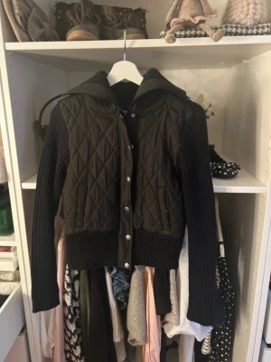 Svart quiltad cardigan jacka - Snygg svart cardigan jacka med quiltat mönster på fram- och baksida samt stickade ärmar och muddar. Jackan har knappar framtill och en bred krage som ger en cool look. Perfekt för dig som vill ha något både bekvämt och trendigt. Står storlek m men sitter mer som en s💓💓