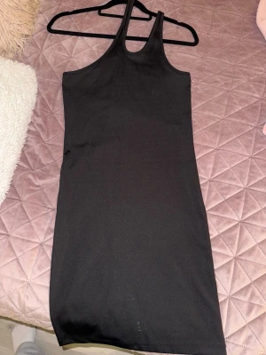 Svart ärmlös klänning - En enkel och stilren svart klänning med ärmlös design och rund halsringning. Klänningen har en rak passform och är tillverkad i ett mjukt, stretchigt material som sitter bekvämt på kroppen. Perfekt för att styla med olika accessoarer.