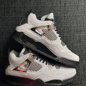 Nike Air Jordan 4 Retro Metallic Silver size 44&42 - Nike Air Jordan 4 Retro med grå mocka, svarta detaljer och metallic silver på snörningsfästena. Snygg meshpanel på sidorna och klassisk Jumpman-logga på hälen. Platt svart sula och svarta skosnören ger en clean och modern vibe.