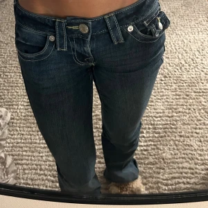 True Religion Joey lågmidjade jeans - Säljer ett par mörkblå True Religion Joey jeans med låg midja och flare-ben. De är typ inte använda alls, så inga defekter eller liknande. Säljer då de inte är min stil.💐🩷