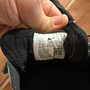 Nike React svarta sneakers med blå detaljer - Säljer ett par svarta Nike React sneakers med blå detaljer och vit swoosh. Skorna har snörning, grov sula och är tillverkade i syntetmaterial. Perfekta för dig som gillar sportig stil och vill ha bekväma skor till vardagen.