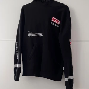 Herrhoodie - Hoodie från H&M med NASA tryck, reflexdetaljer och dragkedjor på magfickan!  Använd enstaka gånger. Längd 70cm axelbredd 46cm