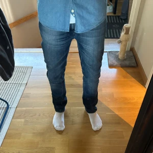 Nudie Jeans - Säljer mina snygga blå jeans från Nudie Jeans. Jeansen har en slim fit passform och är tillverkade i mjukt denim med lätt tvättad look. Väldigt fräscha och knappt använda. 