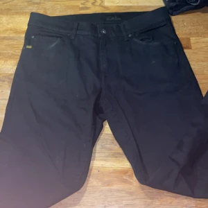 Svarta jeans från Tiger of Sweden - Svarta jeans från Tiger of Sweden i modellen Evolve. Klassisk femficksdesign, raka ben och diskret logga vid fickan. Snygg passform och tillverkade i ett mjukt bomullsmaterial med lite stretch. Perfekta för dig som gillar stilrena och tidlösa jeans.