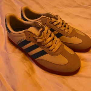 Adidas Samba Sporty & Rich sneakers - Adidas Samba Sporty & Rich sneakers i beige och blått med klassiska tre ränder på sidan. Väldigt snygga och passar för dig som vill ha ett par unika skor🤩helt i nyskick✨OBS! Sulan är inte röd, som det ser ut på bilderna. Tveka inte att skriva om ni har några frågor😉