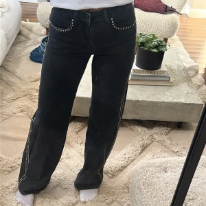 Svarta jeans med nitar längs sidorna - Snygga svarta jeans med raka ben och silverfärgade nitar längs fickor och sidorna. Använt 1 gång. 