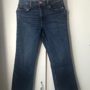 Mörkblå raka jeans Zara - Snygga mörkblå jeans med klassisk femficksdesign och raka ben. Jeansen har en enkel knappstängning och subtila slitningar framtill. Perfekta för en avslappnad och stilren look.
