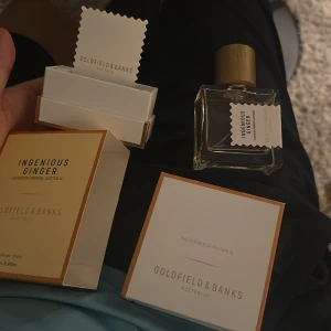 Ingenious Ginger från Goldfield & Banks - Upptäck Ingenious Ginger från Goldfield & Banks, en elegant parfym i en stilren glasflaska med trälock. Förpackningen är vit med guldiga detaljer och ger en lyxig känsla. Perfekt för den som söker en unik doftupplevelse med en touch av Australien.