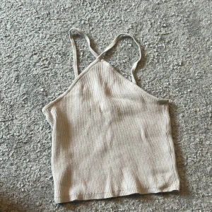 Beige ribbad linnetopp från H&M - Säljer en beige ribbad linnetopp från H&M i storlek XS då den inte kommer till användning längre. Toppen har smala axelband som korsas i ryggen och är croppad i modellen. Använt den ett fåtal gånger så den är i mycket bra skick.