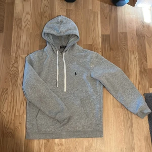 Grå hoodie från Polo Ralph Lauren - Snygg grå hoodie från Polo Ralph Lauren med vit snörning i huvan och klassisk broderad logga på bröstet. Inte en skråma på tröjan! Perfekt för hösten! Det står ju storlek L men jag skulle säga att den passar M. Pris kan diskuteras!