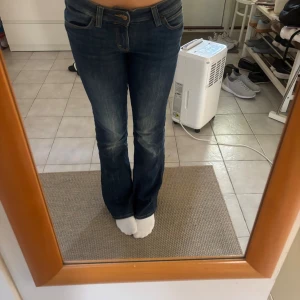 Blå bootcut jeans från Cheap Monday - Säljer ett par blå bootcut jeans från Cheap Monday i klassisk denim med lätt slitning på framsidan. Jeansen har normal passform och är tillverkade i en mix av bomull, polyester och lite elastan för extra stretch. Perfekta för dig som gillar en tidlös look med lite utsvängda ben.