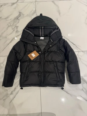 Svart pufferjacka från Burberry - Säljer en svart pufferjacka från Burberry som kan bli till en väst om de blir för varmt jätte bekväm den funkar Som S M 