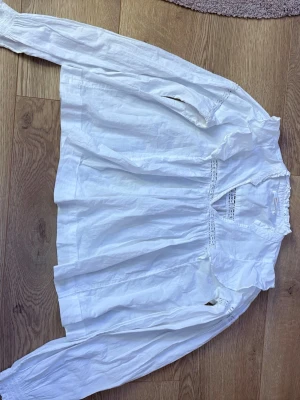 En vit blus  - Vit blus från Gina Tricot i storlek 158/164. Lätt och luftig modell med fina spetsdetaljer framtill och vid axlarna. Långärmad med resår vid ärmsluten och rundad halsringning med liten volangkant. Perfekt till både vardag och finare tillfällen. I gott skick 🌸