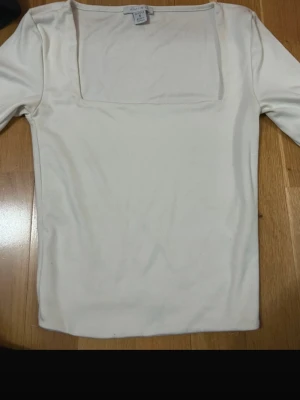 Vit långärmad topp från Amisu - Säljer en stilren vit långärmad topp från Amisu i storlek S. Toppen har en fyrkantig urringning och är gjord i ett mjukt, stretchigt material som känns skönt mot huden. Perfekt att matcha med jeans eller kjol för en clean look.