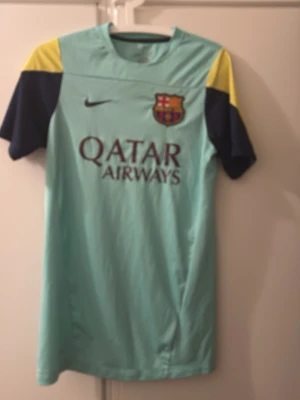 FC Barcelona Nike fotbollströja S - Säljer en FC Barcelona fotbollströja från Nike i ljusblå Dri-Fit polyester med mörkblå och gula detaljer på ärmarna. Tröjan har klubbmärke och Qatar Airways-tryck på bröstet, samt Nike-logga. Perfekt för dig som älskar Barca och vill ha en snygg matchtröja. Dock är texten inne i tröjan borta eftersom lotsnat. 