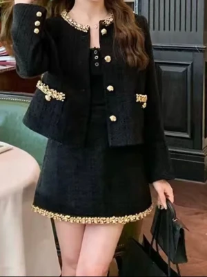 Set 2st Svart jacka  och kjol med paljettdetaljer - Snygg svart kostym från Stone Studio med kavaj och minikjol. Båda plaggen har glittriga paljettdetaljer i guld vid krage, fickor och kjolkant. Kavajen har guldfärgade knappar och en rak, croppad passform. Materialet är grovvävd polyester som ger en lyxig känsla.