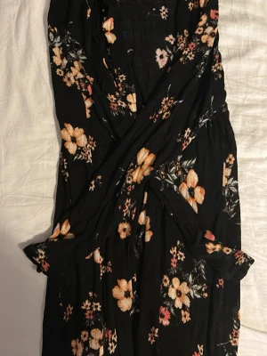 Blommig svart kofta från H&M Divided - Svart kofta från H&M Divided i storlek XL med blommigt mönster i beige, rosa och orangea toner. Lätt och flowy modell med långa ärmar. Perfekt för dig som gillar en chill och snygg stil med romantiska vibbar.