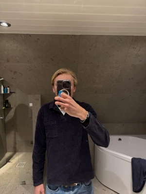 Långärmad piké i frote  - Säljer en mörkblå långärmad piké från East West i frote. Tröjan har klassisk krage, bröstficka och relaxed fit. Perfekt för dig som gillar en stilren och avslappnad look. Jag på bilden är 183 cm