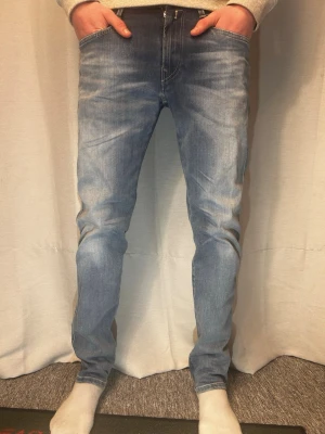 Blåa Replay Anbass jeans - Säljer ett par blåa replay anbass jenas. Står att de är W31 L30. Men känns mer W30 och längd 32. Modellen på bildens är 183 cm lång o väger 70 kg. Skriv vid minsta fundering.