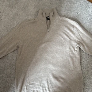 Beige half zip tröja Jack & Jones - Snygg beige tröja från Jack & Jones med half zip och hög krage. Tröjan är långärmad och har ribbade muddar vid ärmslut och nederkant. Storlek xs men sitter mer som S