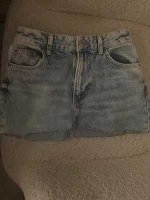 90's denim minikjol från Bershka - Säljer en ljusblå denim minikjol från Bershka, inspirerad av 90-talet. Kjolen har rå kant nertill. Kjolen är jätte fin och är som ny💕