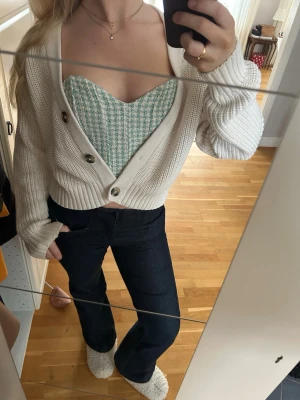 Grönvit rutig korsettopp - Säljer en croppad korsettopp i grönt och vitt med rutigt mönster. Toppen har en snygg sweetheart-urringning och är axelbandslös, vilket ger en trendig och fräsch look. Materialet känns lite tjockare och strukturerat, perfekt för vår och sommar.
