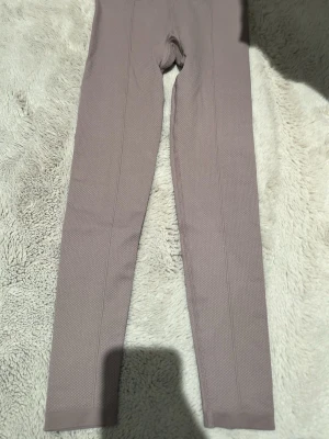 Beige AIMN leggings XS - Säljer ett par beige leggings från AIMN i storlek XS. De har en snygg textur i materialet och sitter tight med hög midja. Tillverkade i stretchigt tyg av 92% polyamid och 8% elastan, perfekta för träning eller chill. Aldrig använt dem, har också fått hänga med ut ur min rensning från garderoben, har bara legat där som sagt. De är i mycket bra skick