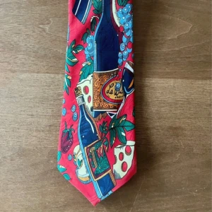 Färgglad fin rolig slips  - Unik Vin & Ost-Slips i Siden - 49 kr!  Upplev det bästa av två världar med denna charmiga vin- och ost-slips i lyxigt siden! Denna unika slips är en hyllning till livets goda ting, med ett färgstarkt motiv av vin och ost. Perfekt för vinprovningar, ostkvällar eller för att ge din stil en touch av kul och elegans. Tillverkad av högkvalitativt siden för en mjuk och lyxig känsla. Säljes för endast 49 kronor - ett kap för en så stilfull och exklusiv slips. Passa på innan den försvinner!