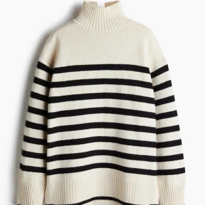 Randig oversized polotröja  - Säljer en snygg polotröja med svartvita ränder och hög ribbad krage. Tröjan är stickad i mjuk ullmix och har breda muddar vid ärmslut och nederkant. Perfekt för dig som gillar klassisk stil med en modern twist.