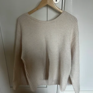 Beige stickad tröja med rosett - Superfin beige stickad tröja med ribbad struktur och öppen rygg som knyts med en bred rosett. 