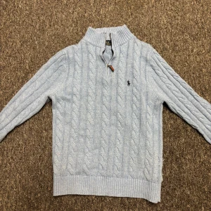 Ljusblå kabelstickad tröja Polo Ralph Lauren - Kabelstickad ljusblå tröja från Polo Ralph Lauren med half zip och hög krage. Den är large men sitter som medium. Har haft ett tag men ändå i väldigt bra skick.