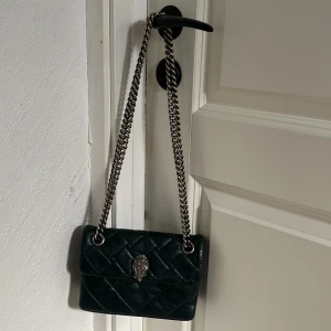 Mörkgrön kurt geiger väska - Säljer min favorit väska i behov av pengar. Väskan är väl använd, men för att behålla färgen har jag målat med en mörkgrön läderfärg. Den har absolut skavanker men inget man tänker på. Insidan är hel. Hör av er med frågor❤️