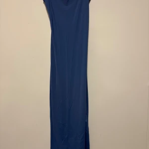 Blå långklänning från Pull&Bear - En stilren blå långklänning från Pull&Bear med enkel och rak passform. Klänningen är ärmlös och har en mjuk, stretchig känsla i materialet. Perfekt för dig som gillar minimalistisk och clean stil. (Använt 1 gång tidigare) priset kan diskuteras.