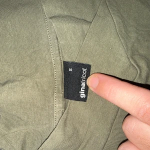 Olivgrön långärmad tröja Gina Tricot - En basic olivgrön långärmad tröja från Gina Tricot. Tröjan har rund halsringning och är i ett mjukt, tunt bomullsmaterial. Perfekt att styla med jeans eller kjol för en enkel och clean look.