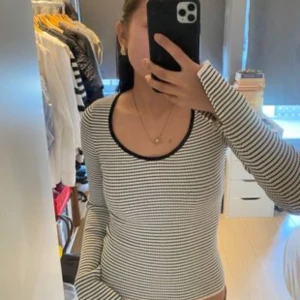 Randig långärmad topp med svart kant - Säljer en snygg långärmad topp med smala svarta och vita ränder. Rund halsringning med svart kant som ger en clean look. Modellen är slim och sitter tajt mot kroppen, perfekt för dig som gillar stilrena basplagg. PRISET GÅR ATT DISSKUTERA!!