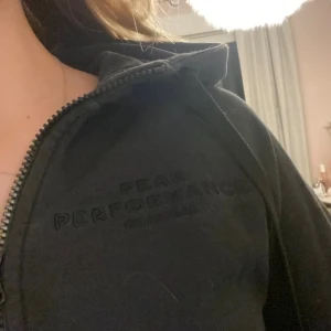 Svart Peak Performance hoodie med dragkedja - Svart hoodie från Peak Performance med broderad logga på bröstet. Tröjan har huva, långa ärmar med ribbade muddar och praktiska fickor framtill. Säljer då den inte används. Den är lite nött vid ärmens slut men ingen som syns. Bara att skriva för mer bilder osv❣️