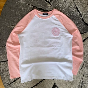 Chrome Hearts longsleeve - || Longsleeve från Chrome Hearts med vita paneler och ljusrosa ärmar. || Tröjan har broderad Chrome Hearts-logga i rosa både fram och bak. || Skön passform och tillverkad i mjuk bomull. || Storlek L || Perfekt för dig som gillar streetwear och snygga detaljer.|| Vid fler frågor skicka ett DM 😼||