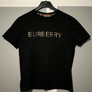 Svart Burberry t-shirt - Snygg svart t-shirt från Burberry. Modellen har rund hals och korta ärmar, tillverkad i mjuk bomull som känns skön mot huden. Perfekt för dig som gillar stilrena designer med lyxig touch, storlek S