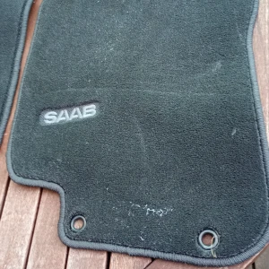 SAAB bilmattor original 2 stycken  - Original bilmattor till SAAB, svart textil med broderad logotyp. Mattorna har fästhål och är i gott begagnat skick med mindre spår av användning och lätt slitage. Perfekt för att fräscha upp bilens interiör. Tillverkade i Sverige. 2 stycken kvar i detta set. Skickas eller hämtas i Skene.