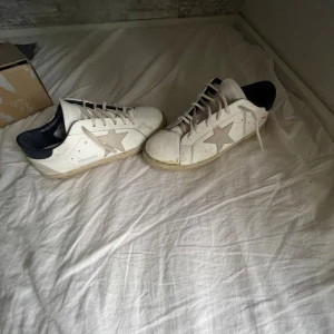 Golden Goose Superstar vita sneakers - Hejsan! Jag ska nu sälja mina golden goose begrund av att jag vill testa något nytt dom är väldigt slitna och har ett rött märke som jag, Själv inte lyckades tvätta bort begrund av att kvaliten är lite sämre än dom andra blir dom väldigt billiga. Tveka inte hör av dig om du har någon slags fundering prister kan diskuteras och byten går jag med på. Ha de bra☺️!