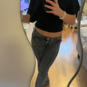 Grå bootcut jeans med fickdetaljer - Säljer ett par grå jeans med cool tvätt och stora fickor framtill. Modellen är bootcut med låg midja och raka ben. Jeansen har synliga sömmar och dragkedja i gylfen. Jeansen är i gott skick och blivit proffesionellt uppsydd för att passs längden 150-165 cm ungefär. Nypris 489 kr.