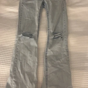 Bootcut jeans med slitningar från Nelly - Bootcut jeans i ljusblå tvätt från Nelly, med snygga slitningar på båda knäna och broderade detaljer på bakfickorna. Modellen har låg midja och klassisk femficksdesign. Perfekt för dig som gillar en avslappnad och trendig look.