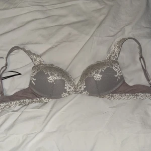 Grå spets-bh med broderade detaljer - Snygg grå bh med vadderade kupor och vacker spets i vitt längs kanterna och axelbanden från intimissmi. Broderade blommor ger en lyxig känsla och axelbanden är justerbara för perfekt passform. Perfekt för dig som gillar romantiska detaljer. Köpte från en på vinted men passade inte mig 💕hon sa att det va 70b så jag litar på det 💕Pris kan diskuteras!!!!