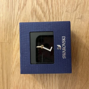 Swarovski bokstav L berlock - Snygg berlock från Swarovski med bokstaven L, dekorerad med gnistrande kristaller. Berlocken  är i bronsfärgad och har en elegant och stilren design som passar perfekt till halsband, armband eller något annat.