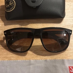 Svarta Ray-Ban Wayfarer solglasögon - Snygga svarta Ray-Ban Wayfarer solglasögon med klassisk fyrkantig form och mörka glas. Kommer med originalfodral och putsduk. Perfekta för dig som vill ha en tidlös och cool look.