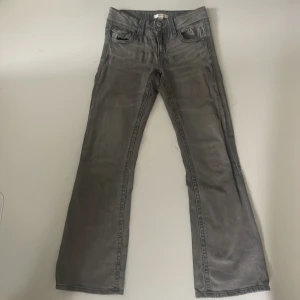Grå bootcut jeans  - Snygga grå jeans från Gina Tricot i bootcut-modell. Jeansen har klassisk femficksdesign, dubbla silverknappar i midjan och är tillverkade i ett mjukt bomullsmaterial. Perfekta för dig som gillar en lite vidare passform nertill.