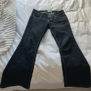Gina Tricot Jeans - Svarta low waisted bootcut jeans med vit broderingar/sydd fr Gina Tricot i storlek 36. Extremt nya, använt två ggr.